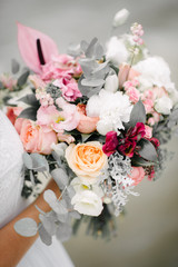 Bride in a wedding dress holding a wedding bouquet in her hands close-up