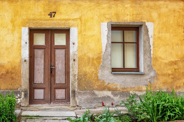 Fototapeta na wymiar Very old door and window in a wall with peeling plaster