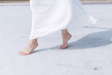 A young woman in a dress walks barefoot. A woman stands without shoes close up