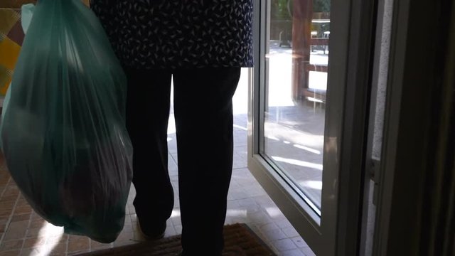 Woman carrying garbage bag and putting plastic trash bag into waste bin container outside house. Gimbal stabilized movement.