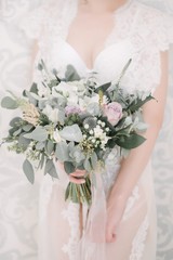 Bride in a wedding dress holding a wedding bouquet in her hands close-up
