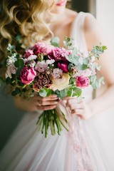 Bride in a wedding dress holding a wedding bouquet in her hands close-up
