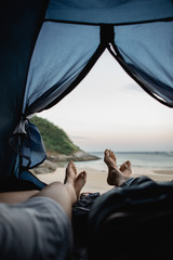 couple resting in a tent on the sandy shore of the ocean - 275033872