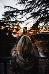 young women take a picture of beautiful sunset on the smartphone