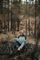 young blonde girl studying a map in the forest