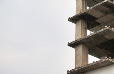 Image of tall old in-finished building with cloudy sky background. Non-safety condition in the city. 