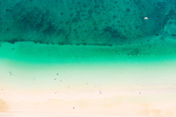 Tropical white sand beach from above. Beautiful aerial view of the beach and the blue sea. People relax on the beach.