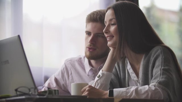 Young couple is working in cafe on laptop and smiling