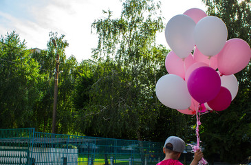 a boy holds in his hand a lot of colored balloons