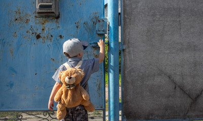 a little boy in the yard with a backpack