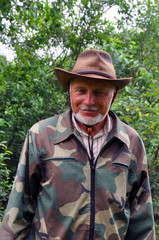 Fototapeta premium Middle aged traveler. Portrait of a handsome adult man with a gray beard and hat in camouflage clothing.