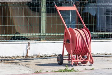 Red fire hose coiled on coil is installed outdoors for emergencies.