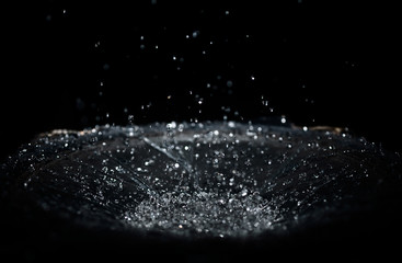 The splash of water drops in loudspeaker on black background. Perpetual motion, music and power concept.