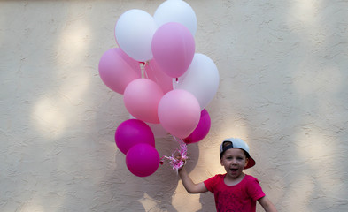 a handsome boy holds laugh in his hand many colored balloons
