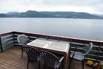 Obraz premium Travel to Norway, view of the fjord from the terrace of the house with wooden furniture