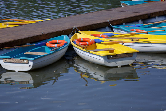 colorful boats with oars and lifebuoys stand on the water of the lake near the wooden pier