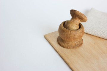 bamboo mortar on a wooden board on a white background next to a linen tablecloth