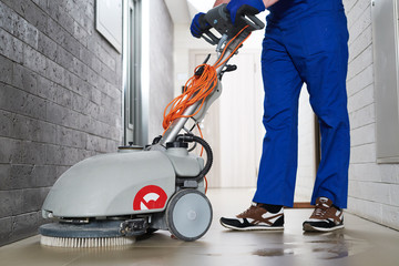 worker with machine cleaning floor in residence hall