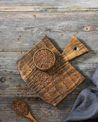 Flax seeds in a wooden bowl on a gray wooden table. Rustic style