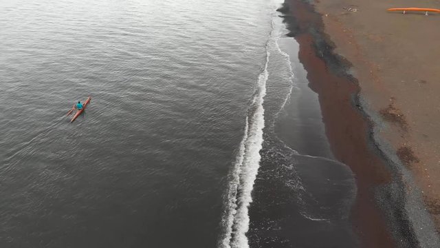 aerial of man paddling his canoe in front of hilo bay canoe club on the big island of hawaii.