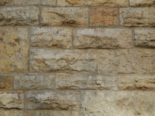 Stone wall in ocher color close up, facing building, beautiful background