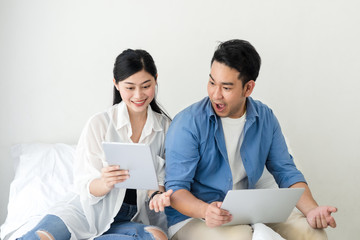 Surprising Asian couple using laptop at home, lifestyle concept.