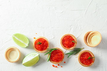 Flat lay composition with tartlets with caviar, rosemary and limes on white background
