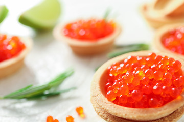 Tartlets with caviar, rosemary and limes on white background, space for text