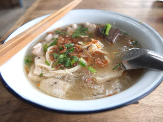 Noodle with sliced pork sausages in local white bowl and wood chopsticks on wood table in Chiang Mai,Thailand