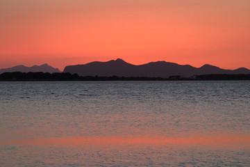 evocative image of the sunset over the sea with a promontory in the background in Sicily