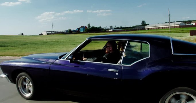 TRACKING Couple traveling together in an old classic vintage 70s muscle car. 4K UHD RAW graded footage