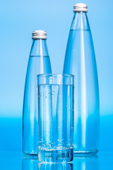Glass water bottles on a light blue background