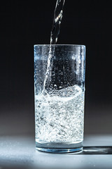Close up pouring purified fresh drink water from the bottle on table