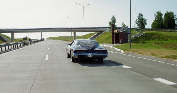 TRACKING Old classic vintage 70s muscle car driving thorough rural landscape. 4K UHD RAW graded footage