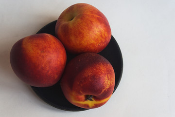 Nectarine on a black saucer. View from above.  Candid.