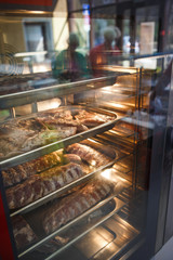 Smoked meat products in the oven smokehouse. A man holding a tray of smoked meat products