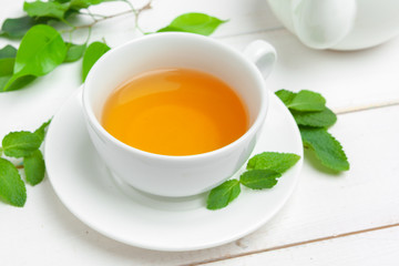 Cup of tea and tea leaves on white wooden table. close up.