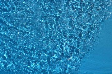Blue and bright water surface with sun refection in swimming pool for background