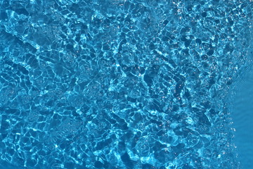 Blue and bright water surface with sun refection in swimming pool for background