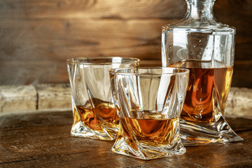 A bottle of cognac and glass on a brown wooden background. Brandy
