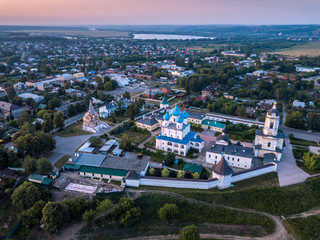 Fototapeta premium Aerial view of the ancient Orthodox Christian monastery, located among the houses and nature in the city of Serpukhov. Early summer morning. Moscow region