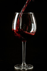 Red wine being poured in a wine glass on a dark background