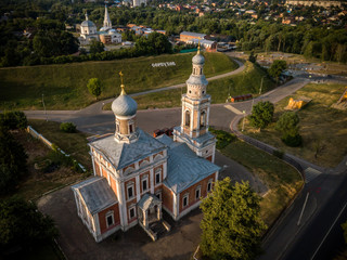 Fototapeta na wymiar Aerial view of the ancient Orthodox Christian monastery, located among the houses and nature in the city of Serpukhov. Early summer morning. Moscow region