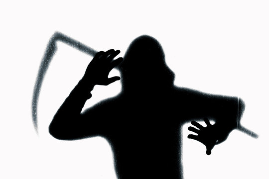 Dangerous man behind frosted glass with a scythe in his hand. Halloween. Black and white image.