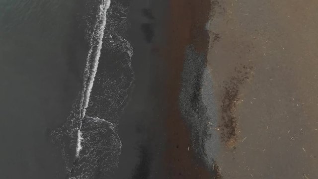 contrasting aerial of hilo bay's massive black sand beach, perpendicular shot strait down at the beautiful coastline of hilo hawaii.