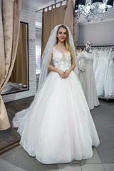 Fototapeta premium Beautiful bride in salon posing in wedding dress
