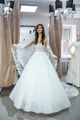 Young woman in wedding dress and veil in bridal shop