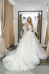Obraz premium Happy bride in wedding dress standing in salon