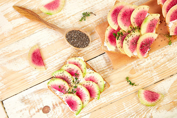 Healthy breakfast toasts from sliced watermelon radish or chinese daikon, chia and cottage cheese on board wooden background. Top view. Flat lay. Copy space.