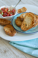 Preparing tasty tomato Italian appetizers -  bruschetta, on slices of toasted baguette, close up view.